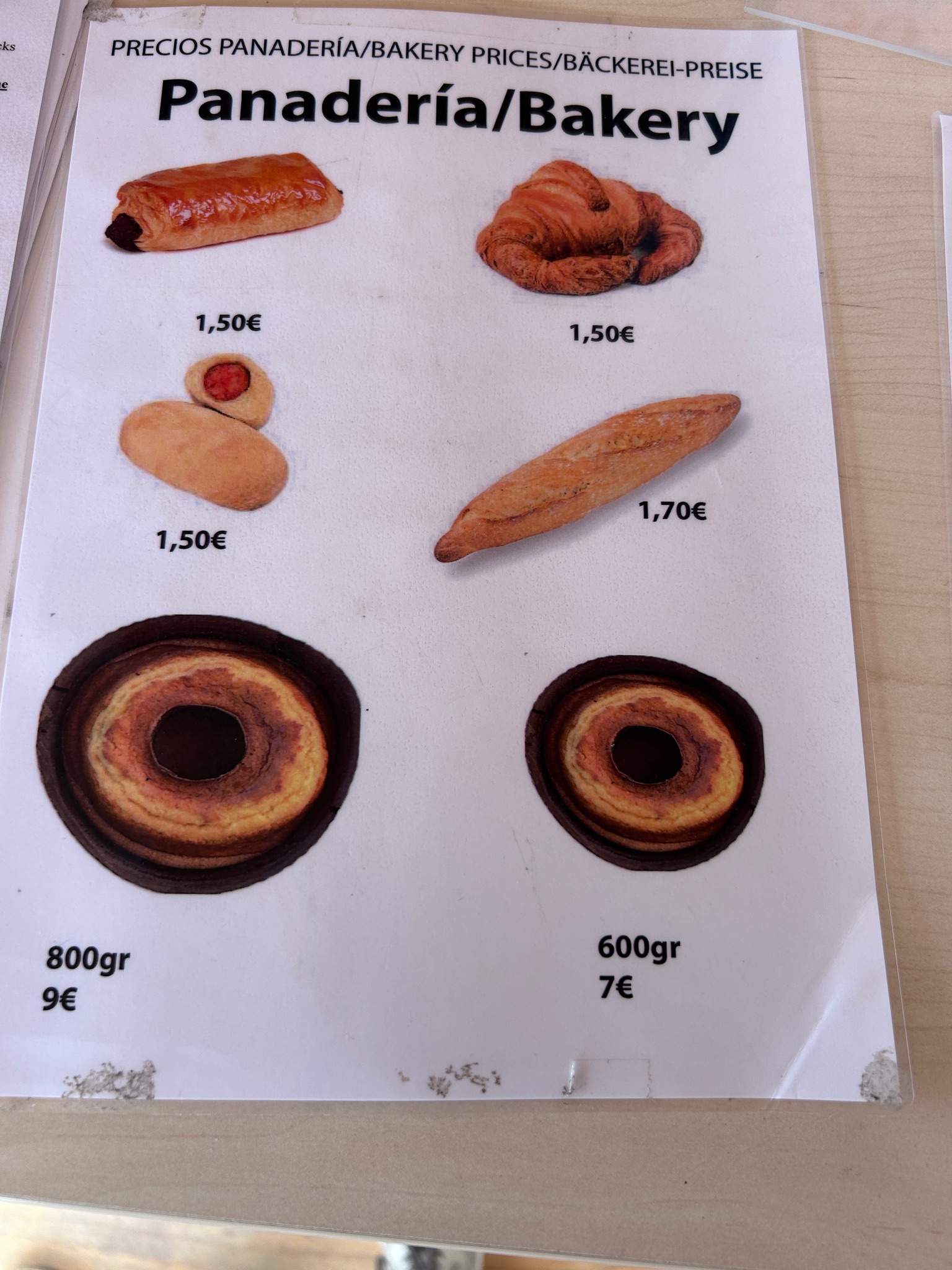 Prijzenbord bakkerij met versgebakken producten zoals croissants, stokbrood en ringvormige gebakjes in Ede.